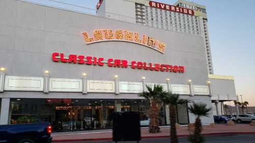 Exterior of a building with a sign reading "Lauglin's Classic Car Collection" and palm trees in front.