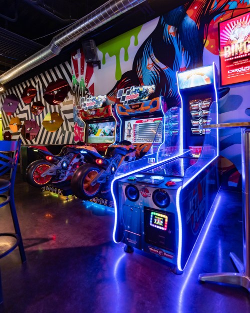 A vibrant arcade scene featuring motorcycle racing games and a colorful, graffiti-style backdrop.