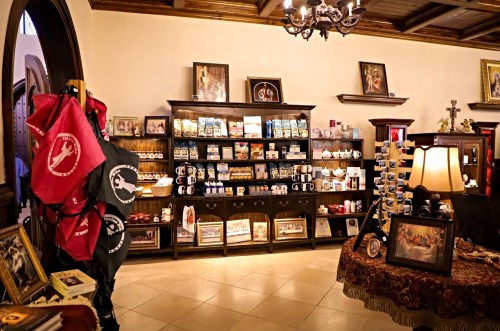 A cozy gift shop interior with shelves of souvenirs, mugs, and decorative items, featuring warm lighting and wooden accents.
