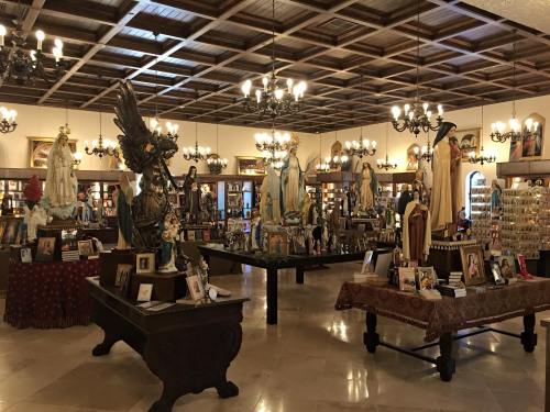 A spacious room filled with religious statues, framed images, and decorative lighting, creating a serene atmosphere.