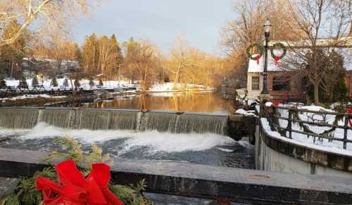 A snowy landscape with a waterfall, decorated with holiday wreaths and a red bow in the foreground.