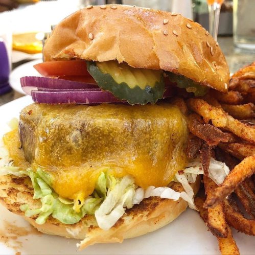 A juicy cheeseburger with lettuce, tomato, onion, and pickles, served with crispy fries on the side.