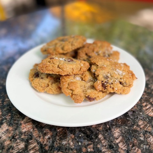 A plate of freshly baked chocolate chip cookies on a textured surface.