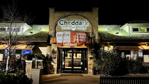 Exterior of Cheddar's Scratch Kitchen at night, featuring a large sign and a banner for takeout and online orders.