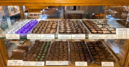 Gourmet sugar-free chocolates and homemade fudge displayed inside a vintage wooden glass showcase at a Michigan candy shop