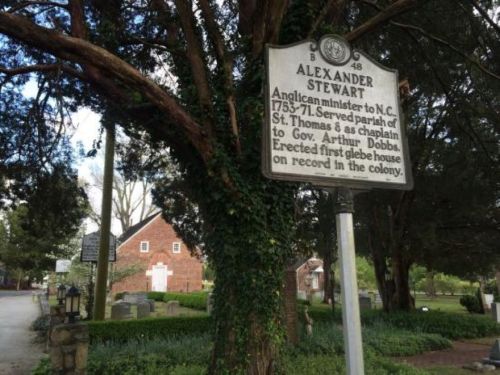 Historical marker for Alexander Stewart, Anglican minister in N.C. from 1753-71, near a tree in a cemetery.