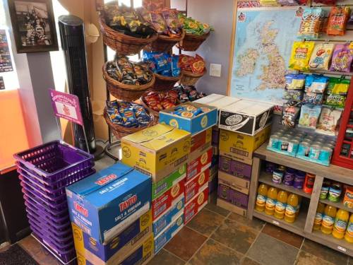 A display of colorful snack boxes and baskets filled with chips, alongside drinks and a map of the UK on the wall.