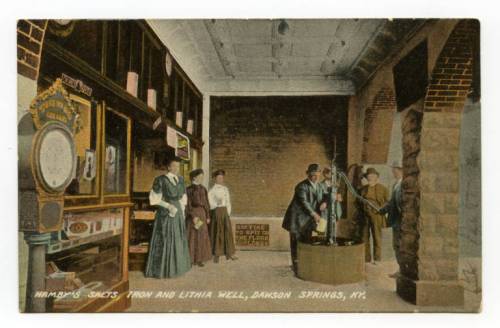 Historic postcard depicting a group of people inside a well house in Dawson Springs, KY, with vintage equipment and decor.
