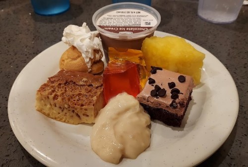 A dessert plate featuring chocolate cake, jello, whipped cream, pineapple, and various sweet treats.