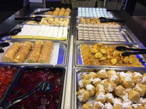 A variety of desserts displayed in trays, including pastries, jello, and cream-filled treats.