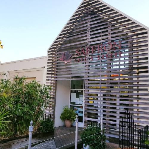 Exterior of Saffron Café & Bakery, featuring a modern design with wooden slats and greenery at the entrance.