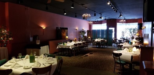 Elegant restaurant interior with tables set for dining, soft lighting, and decorative plants.