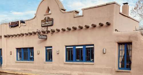 Exterior of Doc Martin's Restaurant, featuring adobe-style architecture and blue windows against a clear sky.