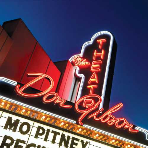 Neon sign of Don Gibson Theater with marquee featuring Mo Pitney and other names, illuminated against a dark background.