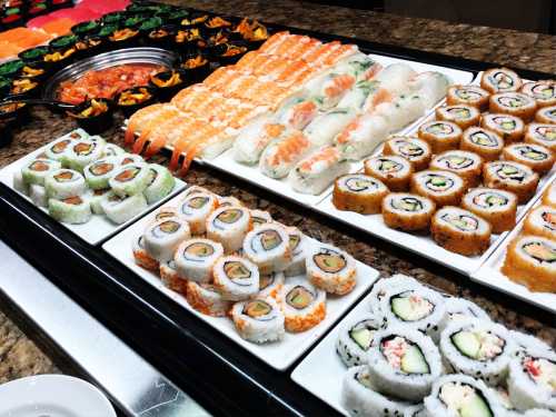 A colorful sushi display featuring various rolls, nigiri, and sashimi on a buffet table.