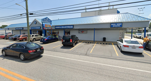 A storefront with a blue roof, featuring a sign for "Cabs & Collectibles," and parked cars in front.