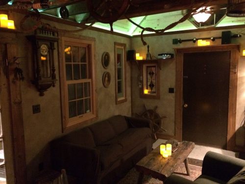 Cozy room with a sofa, wooden table, wall decor, and soft candlelight creating a warm atmosphere.