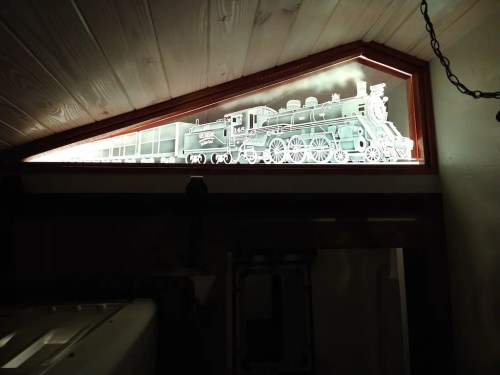 A backlit illustration of a vintage steam locomotive displayed in a triangular window.