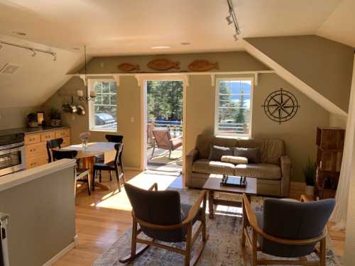 Cozy living space with a kitchen, dining area, and seating, featuring large windows and a view of nature outside.