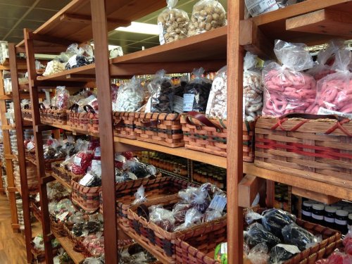 A wooden shelf filled with baskets of various snacks and candies, neatly organized in a store.