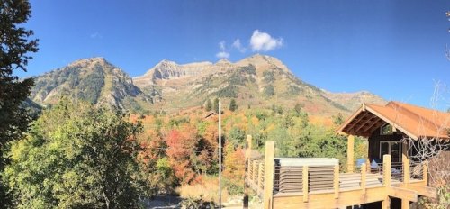 Scenic view of mountains with autumn foliage, featuring a wooden deck and clear blue sky.
