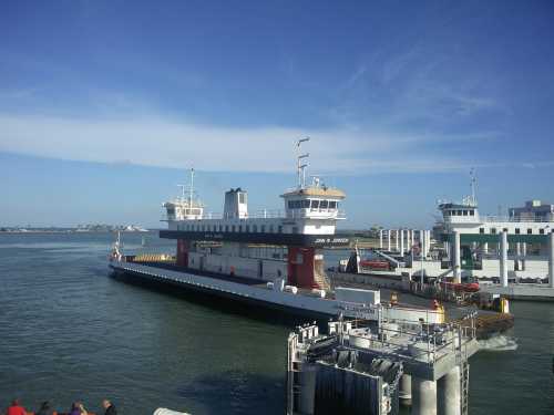 A ferry docked at a terminal on a calm waterway under a clear blue sky.