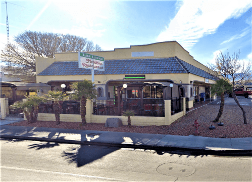 Exterior of a Mexican restaurant with a sign, outdoor seating, and palm trees, set against a clear blue sky.