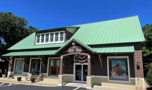 A building with a green metal roof, featuring large windows and decorative banners, under a clear blue sky.