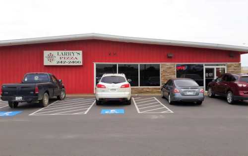 Exterior of Larry's Pizza, featuring a red building, large windows, and parked cars in front. Sign indicates "Open."