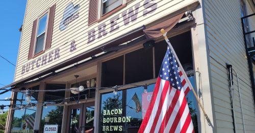 Exterior of a restaurant named "Butcher & Brews," featuring an American flag and a sign indicating it's closed.