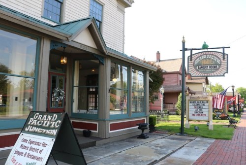 Exterior view of a historic building with a sign for banquet rooms, featuring a welcoming entrance and nearby flags.