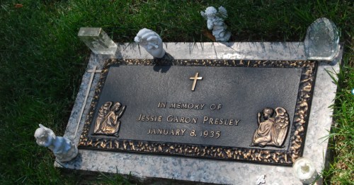 A decorative grey headstone at Graceland featuring a cross and two carved angels.
