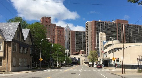 City street view featuring a mix of historic and modern buildings under a partly cloudy sky.