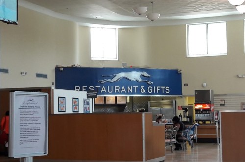 Interior of a restaurant and gift shop with a blue sign reading "Restaurant & Gifts" and seating area visible.