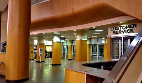 Interior of a modern building featuring a customer service area with wooden columns and a spacious, empty layout.
