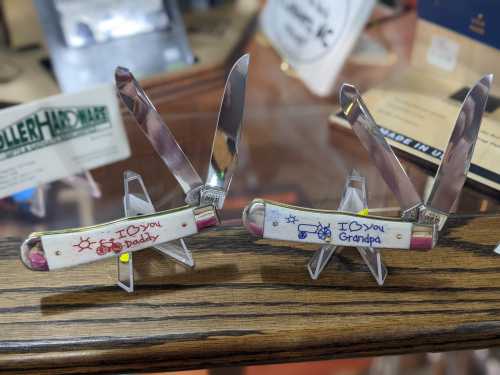 Two pocket knives displayed on stands, each engraved with "I love you Daddy" and "I love you Grandpa."