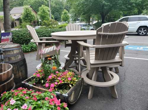 A round outdoor table with four wooden chairs, surrounded by colorful flowers in a planter.