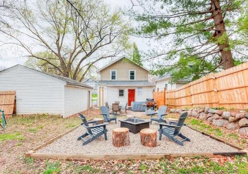 A backyard with a fire pit surrounded by chairs, a wooden fence, and a house in the background.