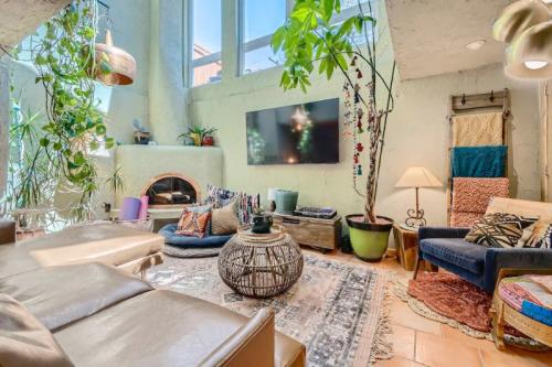 Cozy living room with plants, a large TV, colorful cushions, and a warm, inviting atmosphere.