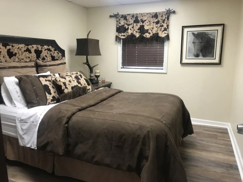 Cozy bedroom featuring a brown and beige color scheme, patterned bedding, and a horse-themed wall decor.