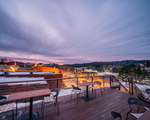 A rooftop view at dusk, showcasing a city skyline with lights and a colorful sky filled with clouds.