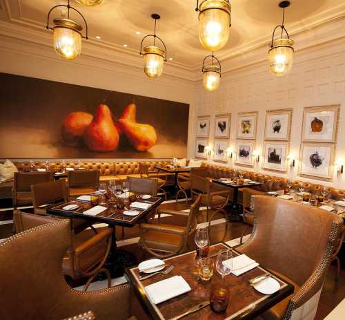 Elegant restaurant interior featuring plush seating, artistic pear painting, and stylish lighting fixtures.