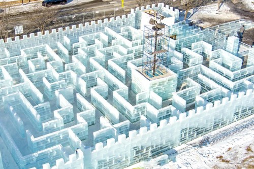 Aerial view of a large ice maze with towering walls and a central structure, surrounded by snow-covered ground.