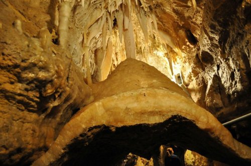 A view of a cave interior featuring stalactites and a large rock formation illuminated by soft lighting.
