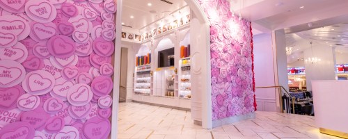 Interior of a vibrant space with pink heart decorations and a display of colorful drinks in the background.