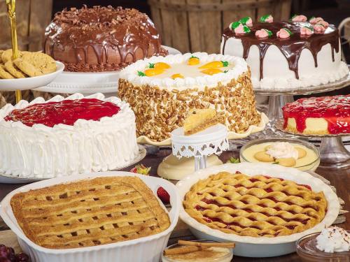 A variety of desserts including cakes, pies, and cookies displayed on a rustic table.