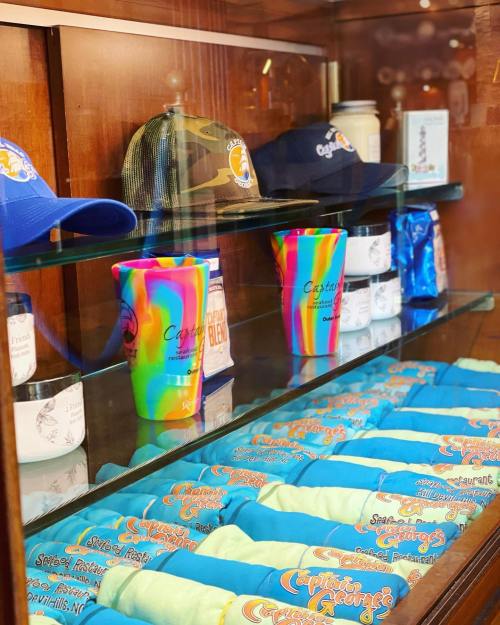 Display case featuring colorful t-shirts, hats, and cups from Captain George's, a seafood restaurant.