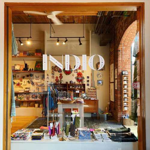 A storefront window displaying the word "INDIO" with various colorful items and decorations visible inside.