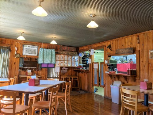 Cozy wooden interior of a diner with tables, a menu board, and warm lighting.