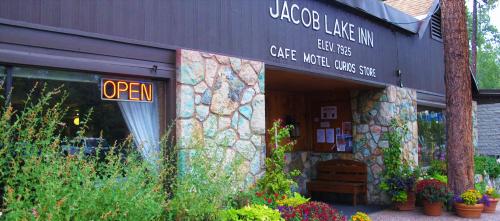 Exterior of Jacob Lake Inn featuring a stone facade, "OPEN" sign, and colorful flower arrangements.